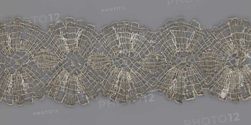 Lace fragment, metal threads, 18th century, Europe, lace fabric, width 8.2 cm, length 27.5 cm., A decorative length of lace with an intricate openwork pattern lies horizontally across a solid background; the lace shows a repeating scalloped design made of interlaced threads forming fanlike and circular motifs, with areas of dense stitching and more open netted sections, and small reflective elements woven into some parts. The visible colors are pale beige or off-white for the lace, metallic-silver highlights where the reflective elements catch light, and a muted medium gray for the background.