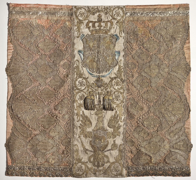 Silk tapestry, 2nd half of the 18th century, Poland. Composition of three vertical stripes: central stripe embroidered on white grosgrain with gold metal thread, bullion, thread, and silk yarn. Upper part shows a cartouche under a crown entwined with a blue ribbon bearing the star of the Order of the White Eagle; the cartouche is divided into five fields containing the White Eagle and Pogon, with the SAR monogram in the center. Below is an eagle with the Ciolek coat of arms in a cartouche on its chest. Royal numerals SAR appear in the corners of the upper and lower parts. Side stripes are pink originally probably crimson grosgrain with wide gold bobbin lace sewn on. Ribbons formerly attached have been removed. Lining of pink cotton or silk? fabric. Height 83 cm, width 88 cm. Subjects/marks: Pogon, White Eagle, Ciolek, SAR monogram; decorative tapestry., A rectangular textile panel with a central vertical band flanked by two wider patterned side panels; the central band is lighter in co...