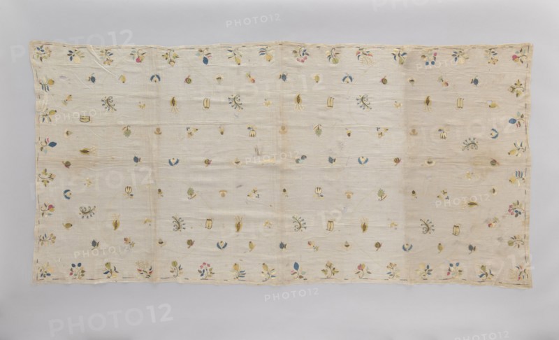 Church napkin tablecloth made of very thin linen batiste covered with multicolored silk embroidery. Ornamentation consists of evenly distributed small patterns of stylized flowers, fruit, animals, and birds. In the center are a fox and a rooster, surrounded by blackberries, apples, plums, several varieties of pears, pea pods, acorns, hazelnuts, mushrooms, strawberries, gourds, tulips, lilies of the valley. Border made of a narrow, shaded strip. Flat embroidery, pierced following the motif, double-sided with silk threads in light yellow, light blue, sky blue, blue, pink, celadon, ochre, and gold and silver thread. Early 18th century, Poland. Fabrics; height 210 cm, width 100 cm., A rectangular pale beige fabric laid flat with a scalloped edge and a border of small floral motifs, scattered across the field are a few small embroidered botanical and abstract shapes in colors including blue, green, yellow, pink, and muted gold, with some elements in darker navy and a few touches of soft bro...