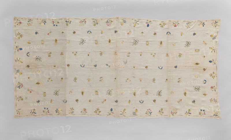 Church napkin tablecloth made of very thin linen batiste covered with multicolored silk embroidery. Ornamentation composed of evenly distributed small patterns of stylized flowers, fruit, animals, and birds. In the center a fox and a rooster, surrounded by blackberries, apples, plums, several varieties of pears, pea pods, acorns, hazelnuts, mushrooms, strawberries, gourds, tulips, lilies of the valley. Border is a narrow, shaded strip. Flat embroidery, pierced following the motif, double-sided, worked in silk threads in light yellow, light blue, sky blue, blue, pink, celadon, ochre, and gold and silver thread. Early 18th century, Poland. Material: fabrics. Dimensions: height 210 cm, width 100 cm., A rectangular light beige textile laid flat with a visible border and scattered small embroidered floral and botanical motifs across its surface; the embroidered details include leaves, buds, and small flower shapes in colors such as blue, pink, yellow, green, and a muted gold, with some moti...