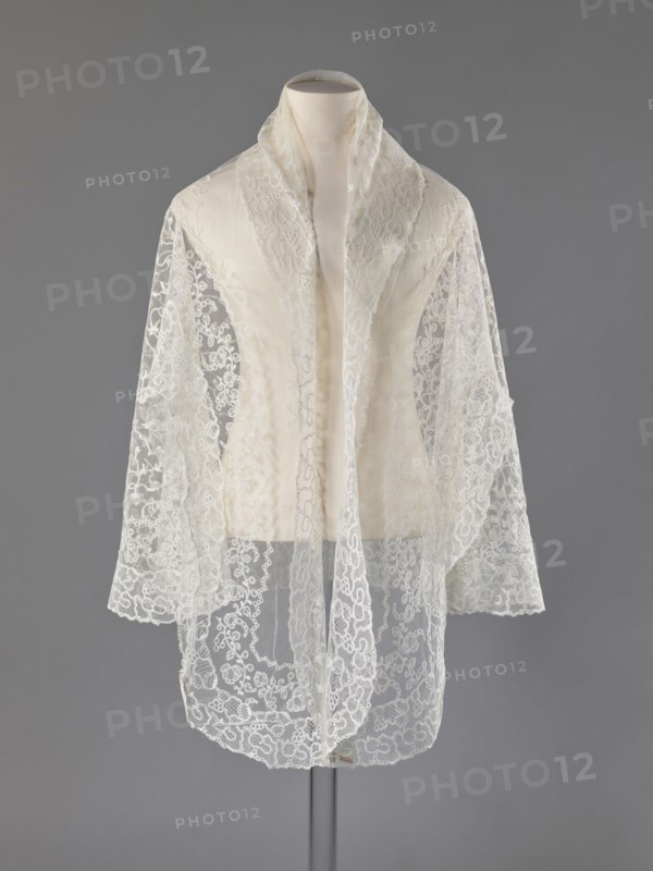 Cape, lace, clothing accessory for women's fashion, 19th century, Europe; length 75 cm, width 192.5 cm., A mannequin torso draped with a sheer lace shawl in shades of white and ivory against a neutral grey background; the shawl has a delicate floral and scrollwork pattern with scalloped edges, long panels hanging down the front and over the shoulders, and semi-transparent areas revealing the smooth fabric of the mannequin beneath; the overall colors visible are white, ivory, grey, and subtle off-white tones.