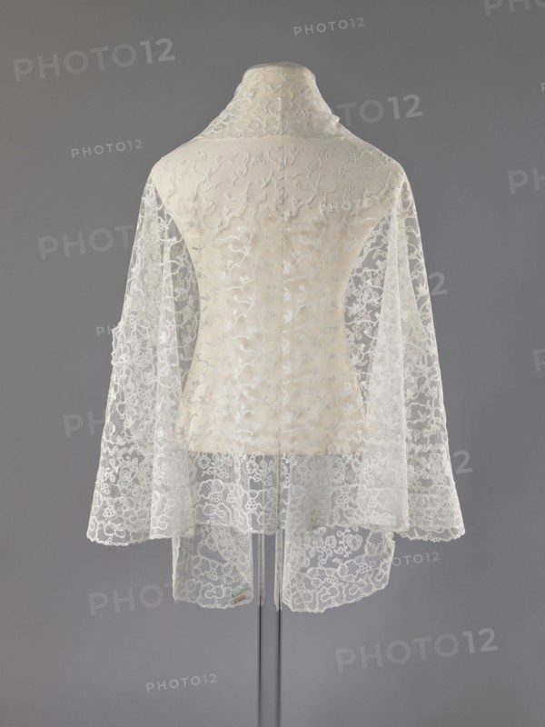 Cape, lace, clothing accessory, women's clothing, fashion, capes, 19th century, Europe, length 75 cm, width 192.5 cm, A mannequin draped with a delicate lace shawl or cape shown from the back, featuring sheer floral lace panels in off-white and cream over a solid cream underlayer; the lace has intricate swirling and floral embroidery with scalloped edges, and the garment has a raised collar in matching cream; the background is a flat medium gray.
