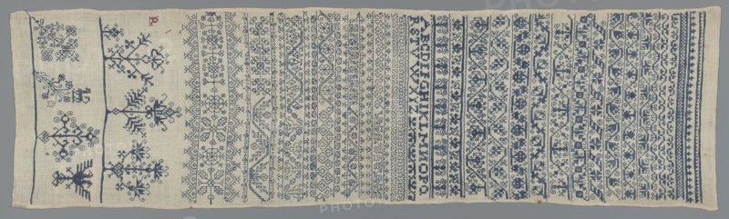 Embroidery sampler, Sampler with a cross-stitch pattern of trails, flower bushes, and letters. Blue embroidery on white canvas. Bands of geometric and floral ornaments with geometrized twigs and leaves; one edge with several larger stylized flower-bush motifs. In the corner, the silhouette of a double-headed eagle. Between the bands, beside various geometrical flower tendrils, a double Holbein-stitch ornament. 17th century, Silesia. Embroidery on fabric; height 81.5 cm, width 23 cm., A rectangular piece of fabric lying flat with a background color of off-white or beige and detailed embroidery in shades of blue and a small spot of red, showing a series of horizontal bands across its width. The left side has a few larger, more open motifs including stylized plant- or tree-like shapes and geometric forms separated by narrow vertical stitched lines, while the rest of the surface is filled with several tightly packed horizontal bands of repeating ornamental patterns such as floral motifs, i...