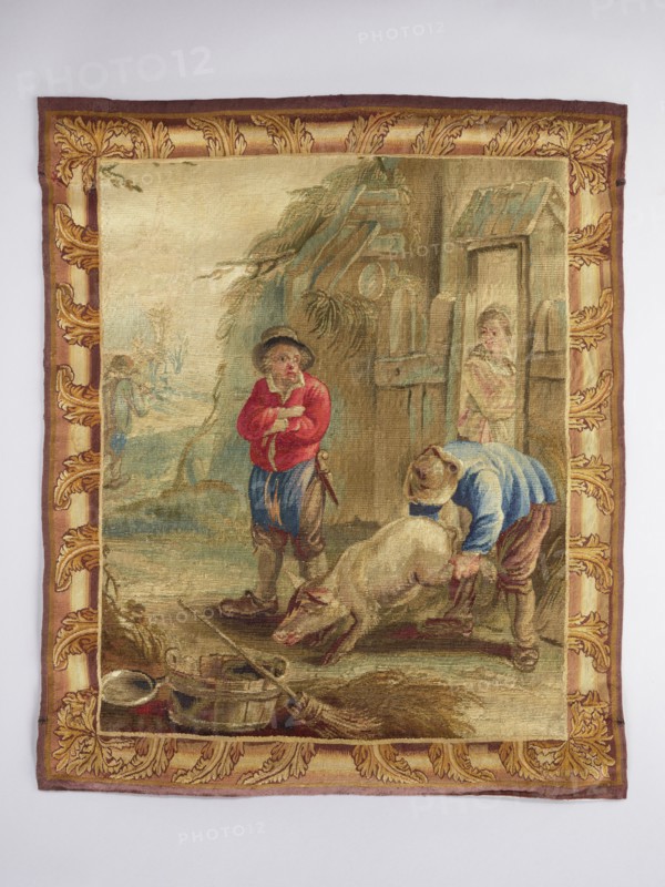 Figural tapestry, floral ornaments, pigs, genre and rural scenes against a landscape background, interior furnishings, decorative fabrics, tapestry borders and weaving. In front of the barn door stand two peasants, one holding a pig by the legs; in the open doorway stands a third figure. In the background, at left, a road and another figure. Border imitates a picture frame with acanthus leaf motifs. Colors: brown, red, green, blue. Tapestry armchair upholstery depicting the 12 months, illustrated with works and games characteristic of the months. Early 18th century, Brussels; fabrics; height 79 cm, width 62 cm., A rectangular woven tapestry with a decorative border in shades of gold, brown, and burgundy surrounds a rustic scene; within the central panel are muted earthy tones of beige, tan, and brown with areas of green and blue suggesting foliage and sky, and touches of red and pink in clothing and faces. In the scene, a person wearing a red top and blue trousers stands with arms cros...