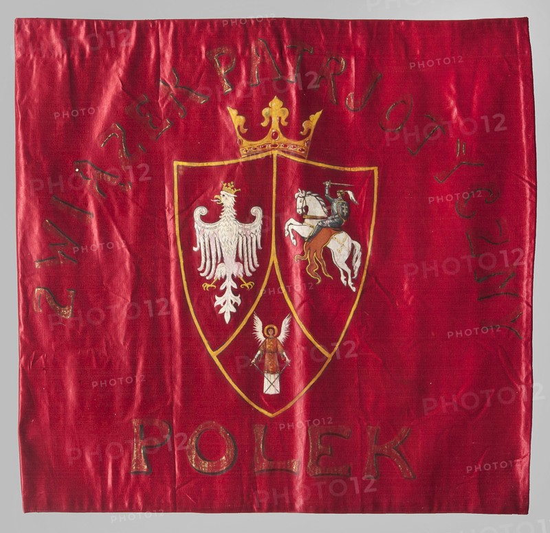 Pennant of the Polish Women's Patriotic Union. One-sided blue ribbon made of red silk fabric. In the center, an oil-painted three-field shield under a crown with the coats of arms of Poland White Eagle, Lithuania Pursuer, and Ruthenia Archangel with swords. Around the inscription: POLISH WOMEN'S PATRIOTIC UNION. Early 20th century, Poland. Materials: fabrics; height 61 cm, width 64 cm., A red square fabric with a glossy texture fills the image, showing creases and a few subtle shadows; near the center is a shield outlined in gold divided into three sections, topped by a gold crown; the left shield section contains a white eagle with a small gold crown, the right section shows a white horse ridden by a figure in dark clothing and a gold saddle, and the lower section has a small figure with white wings and a brown garment; the gold outline and crown, white figures, dark clothing on the rider, and brown and gold accents contrast with the red background.