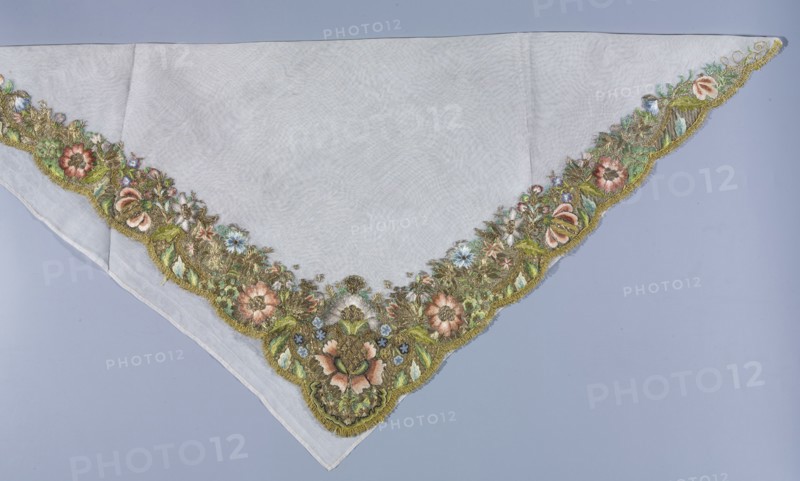 Shawl, shawl; fashion accessory; embroidery; repossession provenance; 18th century, 1st half of the 18th century; Germany; flowers and plant patterns; women's clothing; fabric; length 80 cm, width 80 cm, A triangular pale fabric with a scalloped embroidered border showing a floral design in green, gold, pink, blue, brown, and white, laid against a light bluish-gray background; the central area of the fabric is plain and translucent white, while the embroidered edge features a dense arrangement of stylized flowers, leaves, and textured metallic threads in muted green and gold tones accented by soft pink and blue blossoms and small white highlights.