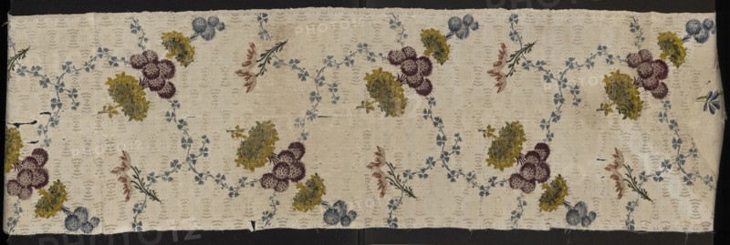 Fabric fragment, silk, Krzeszowice Lesser Poland Voivodeship, fragments of silk patterned fabrics with preserved selvedge, 18th-century silk fabric, floral patterns. Silk fabric fragment with white grosgrain background and a small liseré sub-pattern; colorful floral pattern brocaded with threads in white, light blue, blue, dark blue, dark pink, cherry red, apricot, pale red. Sub-pattern: net-like with small motifs; composed of two intersecting, winding ribbons of tiny blue flowers, one ribbon intersected by multi-tiered bouquets of various flowers in blue, plum, yellow-green. Plot width ?, edge width 0.4 cm. Reported dimensions: height 33 cm x width ? also noted height 106 cm, width 27 cm. 18th century, possibly England., A rectangular piece of fabric with a cream background patterned with a repeating floral design; a few clusters of rounded flowers in purple, yellow, and blue are scattered across the surface, connected by winding garlands of small blue leaves and occasional sprigs wit...