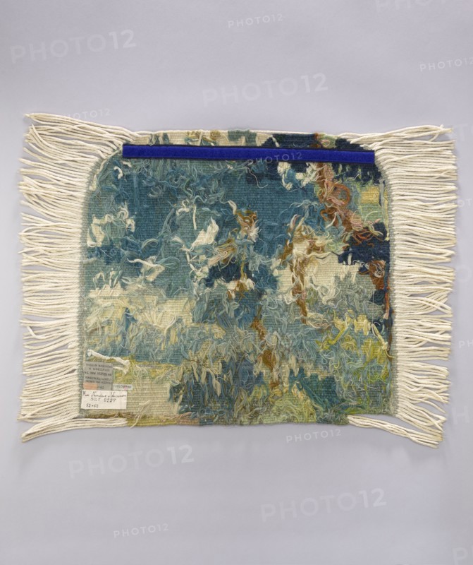 Tapestry chair cover, repossession provenance; motifs: leaves, trees, landscapes, castle buildings on the right, tall trees on the left; interior decorations and furnishings; decorative fabrics. Colors: green, blue, and white. Date: 1st half of the 20th century. Place of origin: Vienna. Material: fabrics. Dimensions: height 53 cm, width 62 cm., A rectangular woven textile with long cream-colored fringe on two opposite edges lies flat against a light gray background, the central woven area showing a textured, loose pile with varied yarns and a mottled pattern in teal, blue, cream, green, yellow, brown, and hints of rust, with a narrow deep blue strip along the top edge; the fringe is cream and the woven field displays tangled loops and tufts creating an abstract, painterly appearance.