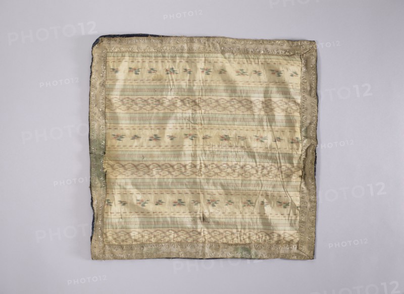 Velum; unknown creator; church paraments; revindication provenance; flowers, leaves, plant ornaments; sacred art; churches and chapels furnishings; 18th century, France; liturgical parament; height 47 cm; width 47 cm, A square fabric with a pale cream and light beige woven center showing horizontal striped patterns and small floral-like motifs in muted green and soft pink, surrounded by a narrow metallic-looking border in a tarnished gold color with areas of darker olive and hints of navy along the outer edge, all placed on a plain light grey background.