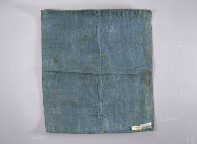 Velum; creator, church paraments; revindication provenance; flowers, leaves, plant ornaments; sacred art; churches and chapels furnishings; 18th century; France; liturgical parament; height 47 cm; width 54 cm, A rectangular piece of fabric laid flat on a lighter background, showing visible creases and fold lines; the fabric is primarily a muted blue with areas of darker and lighter blue and some subtle greenish-blue tones, along with small brownish discolorations and faint worn spots; the edges are slightly uneven and there is a small folded corner at the bottom, with a few tiny irregular marks and variations in texture across the surface.