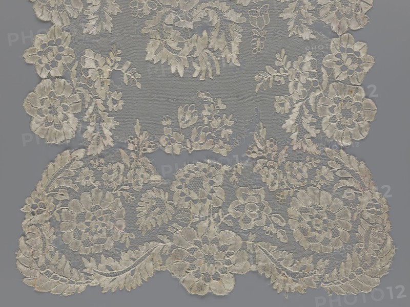 Shawl, shawl, clothing accessory, women's clothing, fashion, lace, serrated edges, in the bends twigs with two flowers, in the middle part curling flower twigs, 19th century, Europe, lace, length 48 cm, width 260 cm, The image shows a piece of delicate lace with an intricate floral pattern laid over a flat background. The lace features a variety of flower and leaf shapes connected by fine net-like threads, with scalloped edges and several clusters of petals and foliage. Visible colors include off-white and cream tones in the lace and a solid gray background.