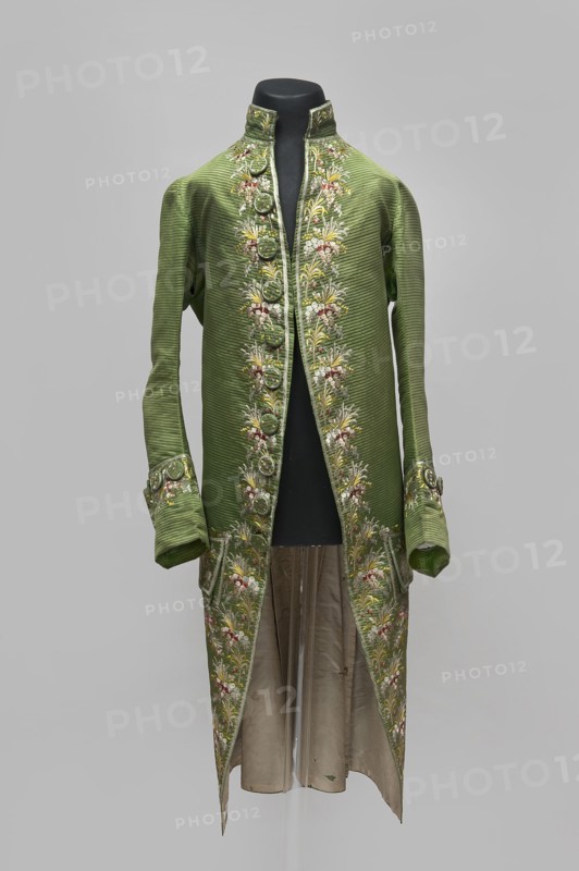Habit à la française, repossession provenance; floral and plant motifs; fashion, men's clothing; embroidery; 18th century clothing. Habit of green silk embroidered with motifs of small bouquets of flowers. Fitted at the top, widened at the back from the waist down with two slit pleats. Fastens at the front with hooks and eyes. Semicircularly cut lapels overlap at breast level and are cut off at the bottom. High, standing collar. Long sleeves set in at elbow height, cut in an arc, finished with wide, slightly protruding cuffs. Side pockets at hip level covered with trapezoidal flaps. Back cut with a center seam; slits at hip level. Center back flaps meet without a pleat. Embroidery runs in a wide band around the edges, cuffs, pockets, collar, and back pleats. Decorative buttons sewn in threes on the cuffs, under the pocket flaps, two at the top of the back pleats, and in the pressed pleats. 1770s, Silesia place of origin; France place of creation. Garment; length 112 cm., A long, green ...