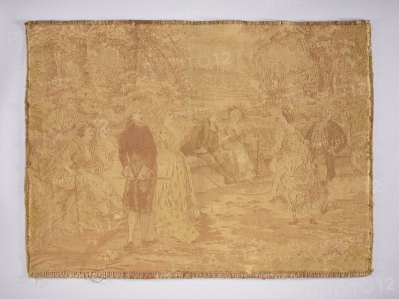 Jacquard tapestry by Alonso Pérez Mariano 1857–1930, co-creator unknown, woven by a manufacturer., noted. Fabrics for interior decoration, decorative fabric/inner furnishing. Genre scene: ladies and gentlemen in Louis XVI–era costume watching a lady jumping rope, set in a park landscape. No border. Monochromatic colors in shades of beige and ochre. 19th–20th century, Europe. Height 73 cm, width 101 cm., A woven textile panel shows a pastoral scene with a group of people in period clothing arranged across a landscape. The fabric has a dominant warm golden-beige tone with variations in ochre and muted tan creating the figures and background through woven shading. On the left, a group of women sit and stand near foliage, while a man in darker clothing stands nearby holding an object; toward the center, seated figures appear to be engaged with each other, and on the right two standing figures face one another. The background includes trees and leafy vegetation woven in slightly darker and ...