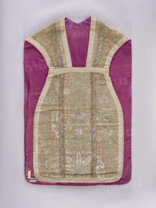 Chasuble, Liturgical vestment made of two types of lace fabrics: the front and sides of the back are silver-colored fabric embellished with a pattern of large plant motifs. The column on the back is satin, straw-colored fabric embellished with colored silk motifs, large fantastic flowers and leaves growing from a small basket. Columns trimmed with silver lace; edges trimmed with wide silver lace. Red silk lining. Height 66 cm; column height 30 cm. Date: 1st quarter of the 18th century front and sides of the back: 1720–25; column on the back: ca. 1715. Place of origin: France. Length 106.5 cm; back width 66 cm., A garment laid flat against a pale background, predominantly showing a deep magenta fabric with an inset central panel of ornate brocade in soft gold, pale green, and muted peach tones; the magenta forms the sleeves and outer border while the brocade panel features an intricate symmetrical floral and foliate pattern with raised metallic threads and a sheen; the brocade is edged ...