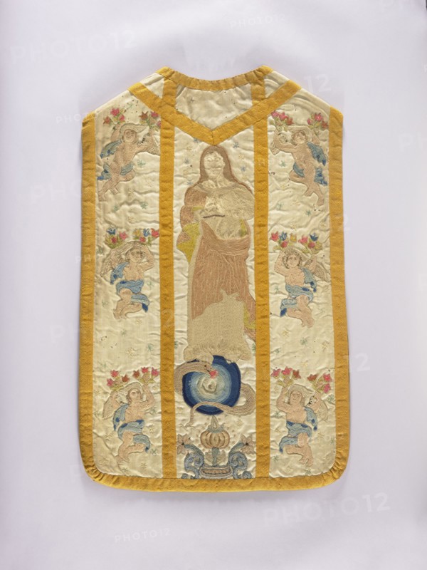 Chasuble, Liturgical vestment, 18th century, Poland. The front column is embroidered with stylized flowers and angels; the rear column: in the center, a figure of the Madonna on the moon; on the sides, angels holding flowers; background covered with tiny stars. Trimmed with smooth woolen braid. Predominant colors: white background with light pink, blue, and sand ornament. Linen lining. Length 96 cm, width 61 cm back., A rectangular embroidered textile with rounded bottom corners and a notched top, bordered and divided by a mustard yellow trim; the central panel shows a standing robed figure in muted beige and brown tones above a circular motif in deep blue and lighter blue, with a coiled serpent-like form in tan; the side panels each feature a group of cherubic figures in pale skin tones with blue drapery and floral crowns in reds and pinks, scattered small star-like embroidered motifs in pale blue and green across a cream background, and decorative scroll elements in blue and tan near...