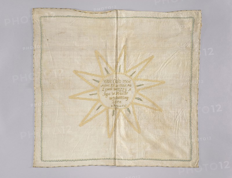 Church napkin. Napkin made of linen with a fairly dense weave. In the middle an inscription embroidered with gold thread on a silk ribbon: Whoever eats my body / and drinks my blood has / eternal life And / I will raise / the last / day / in John in the year 6 / in 54. Around it is an appliquéd narrow grosgrain ribbon in cream and beige forming a circle with three-pronged rays 10, and within them small blue and gold embroidered rays. An identical grosgrain ribbon in three tones of blue is sewn around the edges of the napkin. The ribbons, approximately 8 mm wide, date from the second half of the 18th century, but the inscription was created earlier, as the sewn-on ribbon partially obscures its lower letters. Fabric density: 30 warp and weft threads per cm. 18th century, Poland. Height 76 cm, width 80 cm., A square textile laid flat with visible creases and a stitched border, showing a light beige or off-white background with a pale green decorative inner border and a thin darker edge; i...