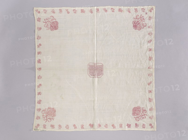 Velum made of white linen batiste; flat, pierced, double-sided embroidery. In the center, in a cartouche, an embroidered inscription in German and the date 1700. Border of small floral sprigs, with one large floral sprig in each corner; in one corner a small monogram EN under a crown. Ornament color light raspberry. Stitches: satin, cord, split, cross; letters and numbers are made with crosses, each cross on three warp threads and three weft threads. Subject: flowers, leaves, plant ornaments; sacred art liturgical vestment., Date: 1700. Place of origin: Silesia. Dimensions: height 77 cm, width 75 cm. Repossession, A square piece of light-colored fabric laid flat against a pale gray background, with a visible vertical crease down the center and subtle wrinkles across the surface; the fabric has a decorative border of small floral motifs in a pink hue running along all edges and larger stylized pink floral designs positioned near the corners, with a small pink embroidered geometric patch...