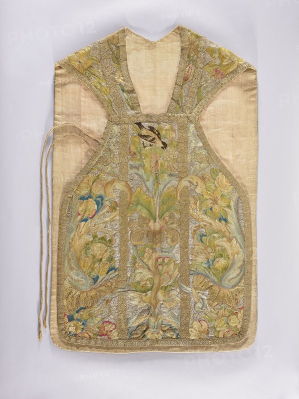 Chasuble, provenance, birds, flowers ornament, fruit ornament; liturgical vestment; plant ornaments; church paraments; sacred art; Embroidered chasuble. On a silver background, a multicolored pattern composed of a fruit vase, floral scrolls, grapes, and birds. Predominant colors: silver background and green, blue, and yellow ornament. Edges trimmed with gold braid with a geometric pattern. Internal divisions marked with strips embroidered with gold thread, imitating haberdashery. Cotton lining. Embroidery on linen canvas with multicolored silk and metal threads in two colors: silver silver plate woven on a white silk base and gold gold plate woven on a yellow silk base. Metal thread embroidery in a laid flat stitch; colored embroidery in split, flat, and knot stitches. E. Soszko; 18th century, Poland. Liturgical vestment. Length 105 cm, width 64 cm back., A textile vestment with a light beige background and ornate embroidered panels in muted gold, green, blue, pink, and cream tones, fe...