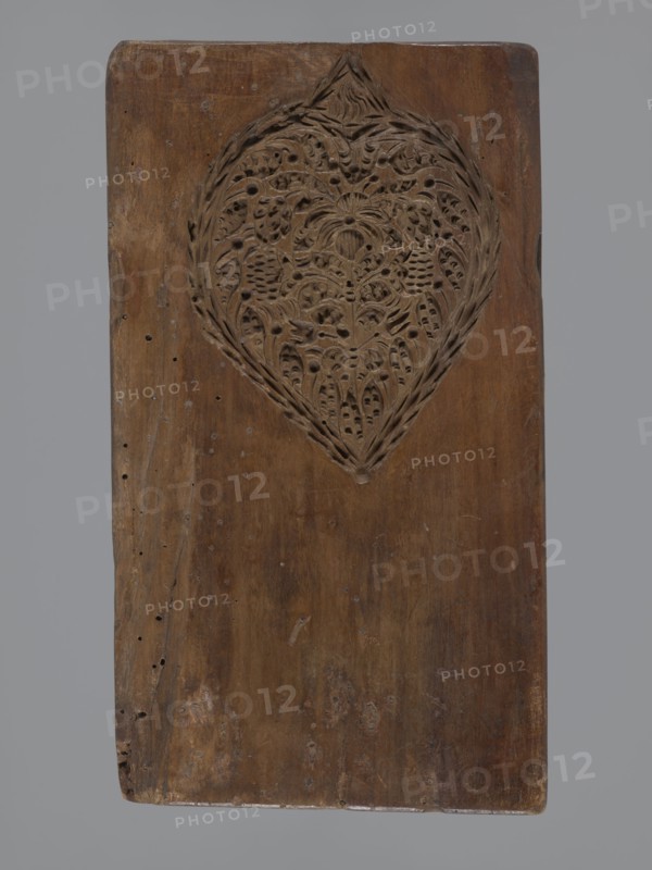 Double-sided gingerbread mould. Obverse: baptism scene; reverse: floral ornament. Genre scenes, gingerbread moulds, folk-style decorations, baptisms, floral motifs, plant motifs, applied art, decorative art, gingerbread, figurative scenes, historical costumes. Double-sided rectangular mould: on one side a genre scene depicting a baptism — a group of figures in 17th–18th century costumes; center a bearded man, probably a priest or pastor, holding a child over a baptismal font, next to him three women in long patterned dresses; the whole group surrounded by an arched window decorated with rich geometric and plant ornament. On the other side a large leaf-shaped ornament containing interwoven floral and plant motifs. 18th–19th century, Province of Silesia 1742–1918. Form: height 26 cm, width 14.5 cm, depth 2.7 cm., A rectangular wooden board with a carved heart-shaped medallion near the top center, the carving featuring intricate floral and leaf-like patterns with pierced details; the boar...
