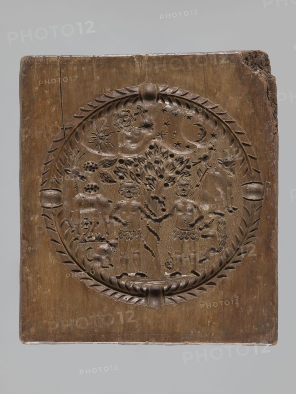 Double-sided gingerbread mould. Rectangular shape; obverse: man in 18th-century attire tricorn hat, justaucorps, culottes, long boots sitting on a goat, carved inscription at bottom: EIN SCHÖNER BOCK EIN GUTER / PFERD IST EINER GN ... DIE ZIGE WERT; complemented by plant and floral ornament. Reverse: Adam and Eve in Paradise wearing leaf loincloths, Tree of Knowledge with coiled serpent; at top a bearded figure holding an orb probably God against a heavenly vault with sun, moon and stars; animals around Adam and Eve include a cat, a deer, a bird, a cow, and a squirrel; composition surrounded by a round decorative frame with a plant twig. Materials/genre: gingerbread mould; style: folk-style decorations, floral and plant motifs, historical costumes, religious iconography original sin. Date: 18th–19th century. Place: Silesia Province 1742–1918. Dimensions: height 21.4 cm, width 24 cm, depth 3.7 cm., A rectangular wooden panel carved with a circular medallion containing decorative relief ...