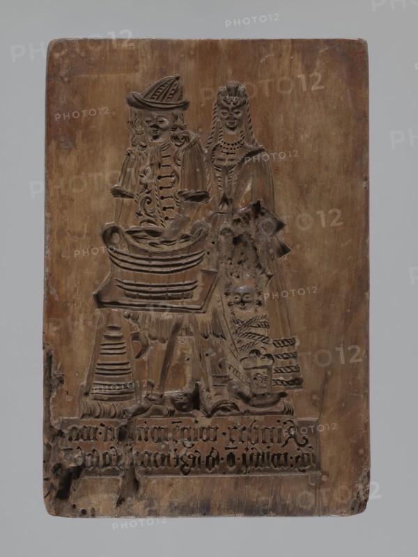 Double-sided gingerbread mould. Obverse: genre scene. Reverse: three depictions. Genre scenes, gingerbread moulds, babies, children, riders, floral motifs, marriages, plant motifs, decorative art, applied art, gingerbread, social satire, rider on a horse iconography. Silesia Province of Silesia, 1742–1918. Double-sided rectangular mould; on one side a genre scene depicting a man standing by a washtub and engaged in washing, behind him a woman holding a baby in swaddling clothes; below a plaque with an inscription in German. Made in Schwabach. Second side: three different motifs: bottom left, a rider in a hat on a horse; above him a rectangular recess containing a second rectangle with the letters I and B carved, surrounded by geometric and plant ornaments; on the right, another tripartite rectangular recess, each segment with a vertical strip of floral decoration; above it carved initials A and H. 18th–19th century. Form dimensions: height 24.7 cm, width 16.8 cm, depth 4.2 cm., A recta...