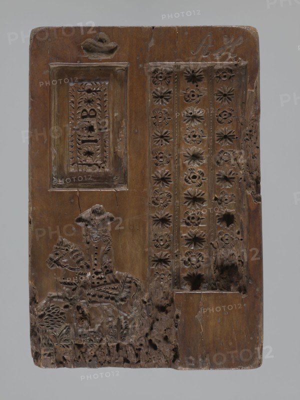 Double-sided gingerbread mould. One obverse: genre scene of a man standing by a washtub washing, behind him a woman holding a baby in swaddling clothes; below a plaque with an inscription in German; made in Schwabach. Reverse: three motifs — bottom left, a rider in a hat on a horse; above him a rectangular recess containing a second rectangle with the letters I and B carved, surrounded by geometric and plant ornaments; right side, a tripartite rectangular recess with a vertical strip of floral decoration in each segment; above it carved initials A and H. Materials: gingerbread mould wood. Iconography: genre scenes, babies, children, rider on a horse, floral motifs, plant motifs, social satire. Date: 18th–19th century. Place: Province of Silesia 1742–1918. Form dimensions: rectangular; height 24.7 cm, width 16.8 cm, depth 4.2 cm., A rectangular carved wooden panel with a brown surface shows a carved scene and decorative patterns; on the left a framed recessed panel sits above a carved f...