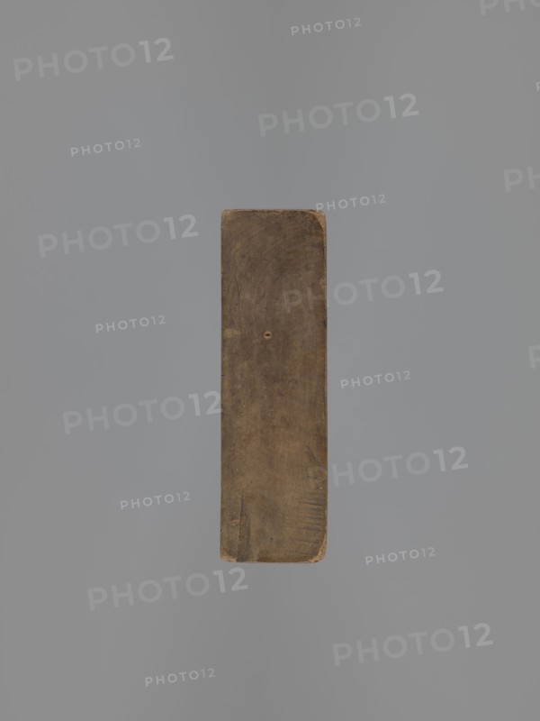 Double-sided gingerbread mould. Obverse: decorative pipe; reverse: nine fish. Double-sided rectangular mould; on one side a long decorative pipe with fluted decoration, on the stem the letter A in an oval, at the mouthpiece two decorative tassels; on the other side, nine stylized fish covered with scales, arranged in a row. Folk-style decorative applied art; gingerbread mould, pipes, fish. 18th–19th century. Province of Silesia 1742–1918. Form. Height 22.7 cm, width 11.5 cm, depth 3.5 cm., A single rectangular wooden block is shown centered against a smooth background; the block has rounded corners, a worn surface with visible grain and small scratches, and a small circular indentation near its center. The visible colors are shades of brown on the wooden block and shades of gray in the background.