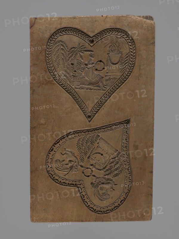 Double-sided gingerbread mould. Obverse: two representations; reverse: four representations. Figurative, genre scenes in folk-style decoration; hearts, altars, Cupid, wreaths, birds, sacrificial altar, erotic scenes. Double-sided rectangular form: one side with two heart-shaped fields — first: female figure in a long dress seated among palm trees, holding a wreath, in front of an altar decorated with a garland with fire burning on it, illuminated by sunrays; second: two cupids hovering over an altar decorated with garlands and holding a wreath. Other side with four hearts, each with a separate scene — first: a bird of paradise among branches; second: a young couple reclining on a chaise longue, with a temple illuminated by the sun and trees in the background; third: a cupid holding a wreath, hovering over an altar with burning fire surrounded by trees, bushes and flowers; fourth: a couple in love holding hands surrounded by trees and bushes. Applied decorative art; Silesia, 18th–19th c...
