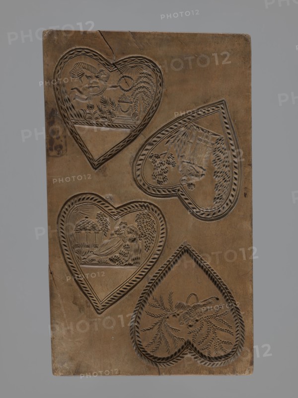 Double-sided gingerbread mould. Obverse: two heart-shaped fields — first: female figure in a long dress sitting among palm trees, holding a wreath, in front of an altar decorated with a garland with fire burning on it, illuminated by sun rays; second: two cupids hovering over an altar decorated with garlands and holding a wreath. Reverse: four hearts, each with a separate scene — first: a bird of paradise sitting among branches; second: a young couple lying on a chaise longue, with a temple illuminated by the sun and trees in the background; third: a cupid holding a wreath, hovering over an altar decorated with garlands with a fire burning, surrounded by trees, bushes and flowers; fourth: a couple in love holding hands surrounded by trees and bushes. Figurative genre scenes with folk-style decorations, hearts, altars, cupids, wreaths, birds, erotic scenes. Applied/decorative folk art, Silesia, 18th–19th century. Form: rectangular double-sided mould. Dimensions: height 23 cm, width 13.8...