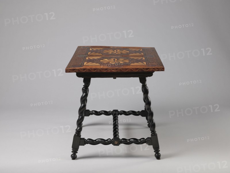 Table, geometric decorations, plant ornaments, rectangular table supported by four straight, spiral legs tilted outwards and sideways, joined at the bottom with an H-shaped tie and at the top with cross stiles connecting them in pairs. Cubes are located at the foot of the table. The tabletop is inlaid and covered with plant twigs and fans oval in the middle, quarters of an oval in the corners, halves halfway along the long sides; with a straight rim decorated with a wave motif. In the type of Baroque furniture from the 2nd half of the 19th century. 17th century, ca. 1660–1690, Spain, Flanders, piece of furniture, table, height 56.5 cm, width 83.7 cm, depth 53.8 cm, A wooden table with a square top featuring intricate geometric inlay in warm brown and tan tones sits on a set of dark, almost black, twisted legs and stretchers; the tabletop shows a patterned border and central decorative panels in shades of brown and golden tan, while the turned legs and connecting bars are deep black wit...
