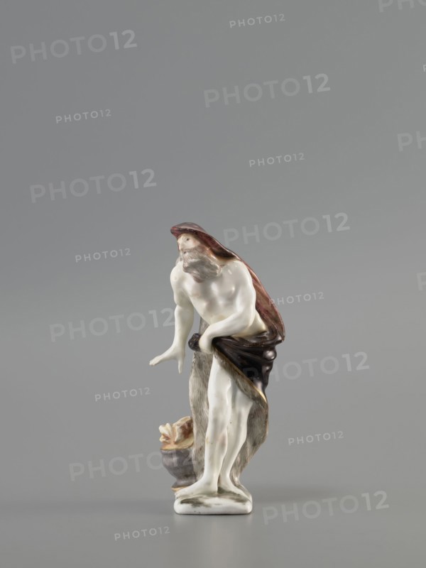 Winter — Allegory. Meissen porcelain factory Koenigliche Porzellain Fabrique, Meissen, ca. mid-18th century 1710–1763. Porcelain figurine, seasons allegory: winter. On a flat, quadrangular pedestal stands an old naked, barefoot bearded man in contrapposto, covered with a fur-lined cloak, a horn thrown over his head flowing down his back and held by the other horn in his left hand at hip level. He leans slightly to the side, warming his right hand over a cauldron with a flame at his feet. Saxony; Meissen. Height: 11.5 cm., A small porcelain figurine of a bearded male figure standing with a draped cloak, shown against a plain grey background; the figure's skin is glossy white, the cloak and drapery show shades of brown and dark brown with some reddish tones, the beard and hair are greyish, and there are touches of beige and muted pink on the face and limbs; the base and a small nearby vessel are off-white and grey with hints of beige, and a few darker brown accents appear where the cloak...
