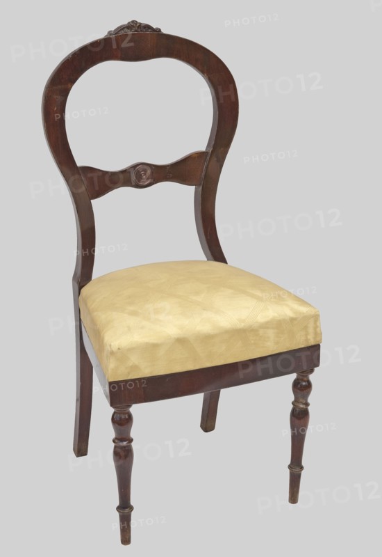 Chair, plant decoration, knobs ornament, Biedermeier and Louis Philippe styles, mahogany. Chair with a trapezoidal upholstered seat removable cushion and a balloon-shaped openwork backrest fastened in the middle with a decorative crossbar with a wavy outline. The front legs are turned and profiled; the rear legs are angular and arched backwards. The top is carved with acanthus leaves, and the center of the backrest crossbar has a decorative knob. Date: 1835–1845. Place of origin: Warsaw . Piece of furniture, seating furniture. Dimensions: height 105 cm, width 48.5 cm, depth 49.5 cm., A wooden chair with a dark brown curved back and carved decorative crest, a curved central back rail with a round carved detail, a padded seat upholstered in pale yellow fabric, turned front legs and plain rear legs, all set against a light gray background with visible wood grain and subtle wear on the finish.