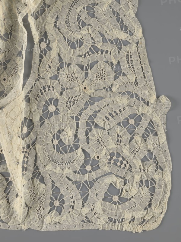Bodice, lace, bodices, women's clothing, fashion. In a pattern of rosettes connected by large spiders and heads. Pattern of stylized floral motifs. 19th century, France. Clothing accessory. Height 36 cm, circumference 63 cm., A close-up view of an ornate textile with an openwork lace pattern showing a group of swirling and floral motifs connected by fine netted threads, with several circular rosettes and rounded openings integrated into the design; the fabric appears delicate with varied stitch textures and scalloped edges, and the visible colors are off-white and gray.