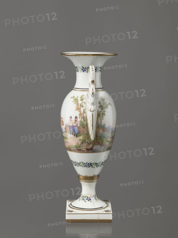 Amphora vase, Imperial Porcelain Factory in St. Petersburg 1744–1917. Amphora vase with an ovoid belly, slender neck flaring at the top, and high foot on a square plinth. Two handles in the form of swans. Colorfully painted: trails of small flowers on the foot, neck, and lower part of the belly. On the belly, two miniatures depicting genre scenes in a rural landscape: a woman with a pole water carrier siudy, koromyslo and a couple with a dog. Base cracked and glued. Early 19th century, St. Petersburg, Russia. Figurine/vase. Height 26.5 cm, width 11.0 cm, depth 9.0 cm. Genre miniatures; genre scenes in landscapes; amphoras; plant decoration; water carriers., A tall, slender porcelain vase with a flared rim and a decorative handle is shown against a gray background; the vase is predominantly white with painted scenes and floral bands, featuring a pastoral scene with people and trees in muted greens, browns, and soft pinks on the body, small blue and green floral garlands near the neck an...