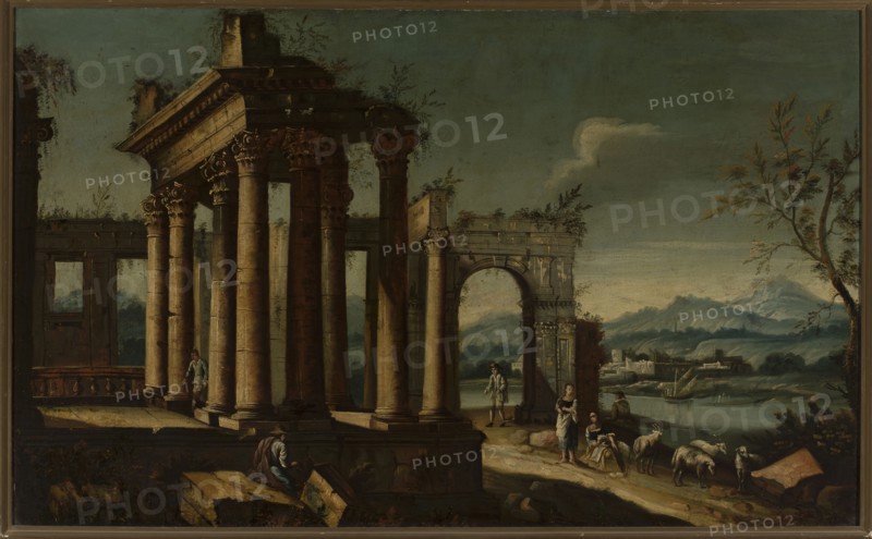 Figures in ancient ruins whim, unknown Italian painter, fantastic architecture, Italian painting, staffage, ruins, whim, 18th century, painting, height 87 cm, width 141.8 cm, A landscape showing classical stone ruins with tall ornate columns and an arched gateway in the foreground, painted in muted browns and beiges for the stonework and dark green and teal for the sky and distant hills; a few human figures in period clothing stand and sit near the ruins, rendered in earthy tones of brown, gray, blue, and muted red; a small group of sheep grazes near the figures, colored white and gray; a lone tree with branches and sparse leaves appears on the right in shades of brown and green; a body of water and low buildings sit in the middle distance beneath a band of pale bluish-gray sky with a single pale cloud, and scattered rocks and vegetation in browns and greens occupy the foreground.