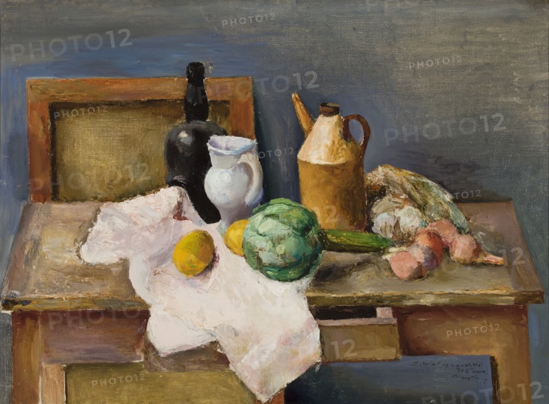 Still life, Waliszewski, Zygmunt 1897-1936 painter, Paris Committee artistic group; 1924-1934, contemporary painting, interwar period, still lifes, lemons, artichokes, onions, bottles, 1925, Paris, painting, height 54 cm, width 73 cm, A still life scene shows a wooden table with a light-colored cloth draped over its edge, on which a group of objects is arranged. There is a dark bottle and a white pitcher standing near the back, and a tall tan jug with a handle and spout nearby. A green round vegetable sits toward the front next to a few yellow fruits and a long green vegetable. A cluster of pinkish root vegetables and a pale leafy item rest to one side. The surface and background display muted tones of gray, blue, brown, and ochre, with highlights of white, green, yellow, pink, tan, and black.