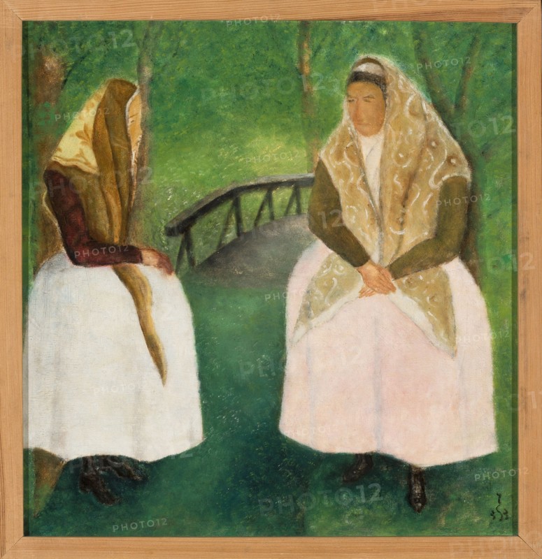 Spychalski, Jan 1893–1946 painter, folk costumes, 1933, Poland; painting; height 41 cm, width 40 cm, A painted scene of two seated women in a green outdoor setting, each wearing headscarves and long dresses; one woman on the left wears a brown headscarf, a dark brown top, and a white skirt, while the woman on the right wears a patterned beige headscarf, an olive green top, and a pale pink skirt; there is a dark curved bridge or railing behind them and a backdrop of green trees and grass, with the ground rendered in darker green tones and the painting shown within a light wood frame.