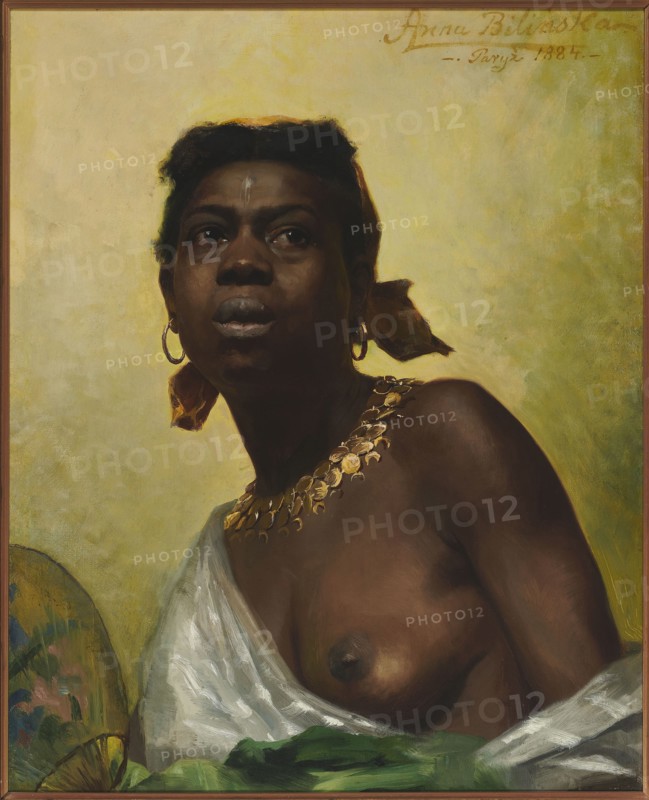 Black woman, Bilinska-Bohdanowiczowa, Anna 1854–1893 painter, jewelry, female semi-nudes, earrings, fans, necklaces, academism style, Académie Julian Paris; 1868–1907, women's emancipation, slavery, Polish painting, portraits, three-quarter portraits, female portraits, women's art, masterpiece, 1884, Paris, painting, height 63 cm, width 48.5 cm, A portrait of a dark-skinned person shown from the chest up against a pale yellow-green background, wearing a white draped cloth over one shoulder and a green cloth at the bottom edge, with a gold necklace made of circular elements and gold hoop earrings, a yellowish-brown headscarf tied at the back, short dark hair, and a small light mark on the forehead; the person has full lips, a contemplative upward gaze, and warm brown skin tones with highlights and shadows.