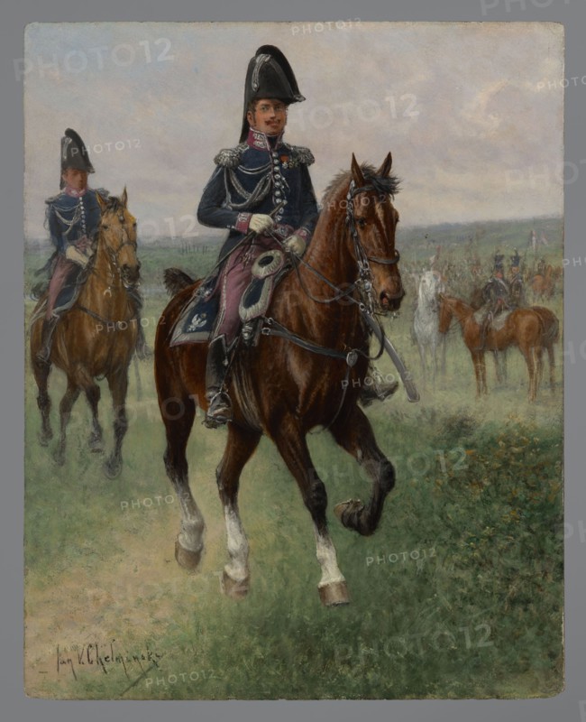 Adjutant Commander of the General Staff and his adjutant, Chelminski, Jan 1851–1925 painter, early 20th century, painting, height 27 cm, width 22 cm, A mounted rider in a dark uniform and a tall black hat sits astride a large brown horse with white markings on its lower legs; the rider wears gloves and decorative shoulder cords and has a sash and ornate saddlecloth in dark blue and reddish tones, while the horse has leather tack and a bit. Behind and to the left, another rider in a similar dark uniform on a lighter brown horse is visible, and in the hazy background a group of mounted figures and horses in muted browns and grays stand across a grassy plain beneath a pale, cloudy sky; the foreground shows green grass with patches of brown earth and some small yellowish flowers.