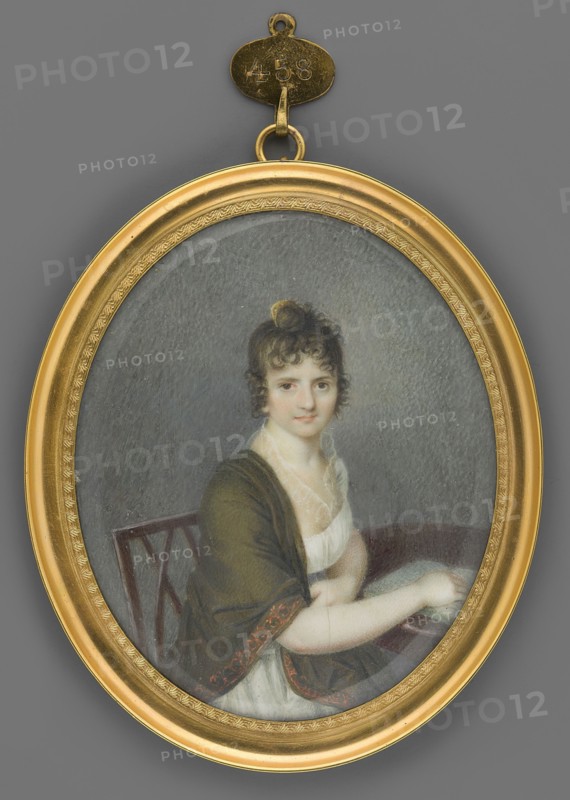 Portrait of a Woman Sitting at a Table, unknown painter. Interiors office, table, chair; young woman in Empire dress with high neckline and shawl; portrait of woman face en face, body right, knee-length, 3/4 half-figure to the right, head almost straight. Seated at a round table with her right hand resting on an open book. Black hair tied on top of the head with a yellow comb; brown eyes. White Empire dress with high neckline; olive taffet shawl with a ginger border on her shoulders. Brown chair; gray background. Miniature, 1808; height 7.6 cm, width 6.5 cm. Frame: gilded bronze, narrow profiled rim with palmette motif around the center., An oval framed miniature portrait shows a seated woman with pale skin and dark curly hair styled up with a small loop at the top, wearing a white dress with a low neckline and a dark shawl draped over her shoulders that has a decorative edge; she rests her arms on a surface beside a wooden chair back with a geometric pattern. The frame is golden with ...