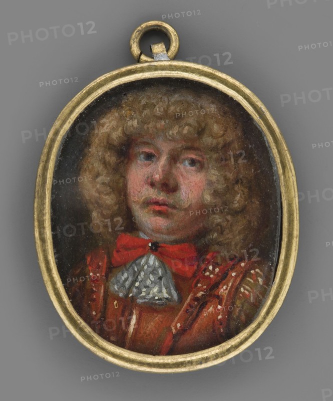 Portrait of a man in a yellow tunic, leather armor and with a red jabot;, Clothing: tunic, armor, jabot, bow. En face, shoulder-length male portrait of a young aristocratic-looking man with brown eyes and blond curled hair in a lion-style wig. He wears a white shirt hem and a red bow fastened with a black stone at the neck, a greenish-white jabot, and brown leather armor over a sandy-brown jerkin; brooch visible. Fragment of armor suggests soldier. Background: dark brown. Binding: narrow, profiled brass frame. Miniature, 1670, Germany. Height 3.4 cm, width 2.8 cm., An oval pendant with a gold-colored frame contains a painted portrait of a person with curly light brown hair, a fair complexion with pinkish tones on the cheeks and lips, and a neutral expression. The person wears a red bow at the neck and a garment in shades of red and brown with decorative highlights, plus a small triangular lace-like piece in a pale grayish color at the throat. The background inside the pendant is dark, ...