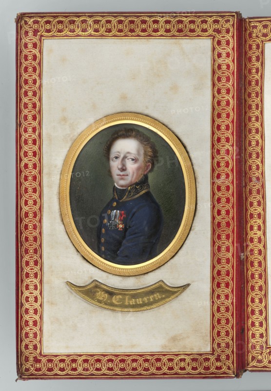 Portrait of the writer Heinrich Clauren 1771–1854, painted by Karl Gottlieb Heun 1771–1854 painter. Miniature portrait 1812, bust turned three-quarters to the left: dark blond hair, gray eyes, white shirt hem, black scarf, navy blue uniform with gold-embroidered collar, gold buttons, wearing three orders. Male portrait to the waist, torso left, head right; middle-aged man; soldier. Background olive-gray. Inscribed dimensions: height 6.3 cm, width 5.0 cm. Frame: gilded bronze., A framed oval portrait of a light-skinned man with short brown hair wearing a dark blue uniform with decorative collar and a few medals on his chest, set against a dark green background, mounted in a gold oval frame on a cream-colored panel that shows some brownish spots, all surrounded by a red border with intricate gold braided decoration and a gold crescent-shaped plaque beneath the portrait.