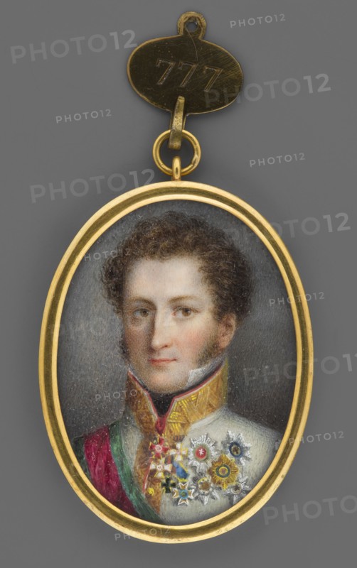 Prince Ernest I of Saxe-Coburg-Gotha 1784–1844 in a general's uniform of the Austrian army, formerly attributed Prince of Schwarzenberg; miniature 1814–1815, height 4.6 cm, width 3.3 cm. Shoulder-length, 3/4 left, almost en face; curly brown hair, brown eyes, white shirt collar, black neck scarf. White Austrian army uniform with collar and fastening trimmed in gold braid. Around the neck: red cross on a red ribbon of the Russian Order of St. Alexander Nevsky; below it the Prussian Order of the Red Eagle. On the chest: Russian Order of St. George, 4th Class; Saxon Order of St. Henry; Austrian Cannon Cross; and five stars of the Austrian Hungarian Order of St. Stephen, Russian Order of St. Andrew, Saxon Order of St. Henry, Saxon Order of the Rue Crown, and Prussian Order of the Black Eagle. Right shoulder bears the red ribbon with green edges and star of the Order of St. Stephen. Background gray-brown. Binding: gilded bronze, narrow rim. Handwritten German inscription on the reverse read...