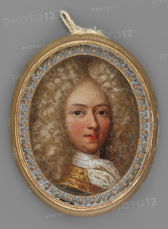 Portrait of a young man in a light lion-style wig self-portrait?, Netscher, Caspar 1635/1636–1684, male portrait, aristocratic subject, lion-style hairstyle. Bust 3/4 left, lion-style wig parted in the middle and falling in curls over the shoulders, high forehead, dark eyes, regular features, pink cheeks and lips. A white lace cravat tied in a knot at the neck; the collar is richly braided with gold and has a wide red edge. Background almost invisible. Oval wooden frame with plaster ornaments around the rim, gilded and patinated in green and blue. 1680, miniature; height 4.4 cm, width 3.5 cm., An oval painted portrait of a person with pale skin and rosy cheeks, shown from the shoulders up and wearing a voluminous curly wig in shades of light beige and cream, set within a decorative oval frame with metallic gold and muted bluish-gray details; the subject has brown eyes and slightly red lips and is dressed in a garment with white fabric at the neck and a richly patterned section in gold ...
