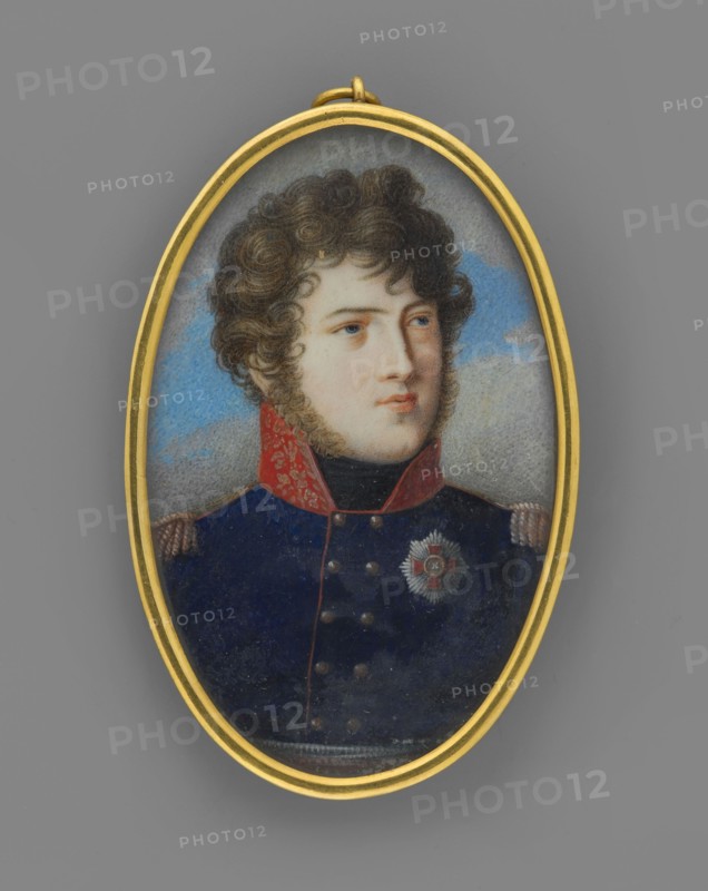 Charles Louis of Baden 1786–1818, Prince of Baden, son of Charles Louis and Amalia Frederick of Hesse-Darmstadt; male portrait in uniform with orders; commander/soldier; miniature, ca. 1812; height 6.0 cm, width 3.8 cm; painter unknown., An oval pendant with a gold frame contains a painted portrait of a young person with curly brown hair and light skin, shown from the shoulders up against a cloudy blue and gray background; the subject wears a dark blue military-style coat with a high red collar and gold details on the shoulders, and there is a decorative star-shaped badge on the chest. The visible colors include gold, brown, light skin tones, dark blue, red, blue, gray, and black.