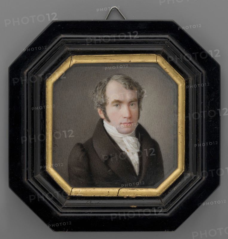 Portrait of Pastor Krauss, court chaplain of the Counts zu Erbach-Erbach, by Johannes Gauff 1804–1858. Miniature portrait, 1840–1850, Germany. Shoulder-length men's portrait 3/4 right showing clergy pastor dressed in a brown-gray tailcoat, white shirt, cravat and waistcoat; gray-gray hair, sideburns, gray eyes. Sandy-gray background. Bust view. Black varnished wood binding with gilded rim inside. Height 7.5 cm, width 7.5 cm., A framed portrait of a man shown from the chest up wearing a dark brown coat and a white cravat, with light skin and short wavy grayish-brown hair and sideburns, set against a neutral gray background; the portrait is enclosed in an octagonal inner frame with a gold-colored border and an outer black frame that has a glossy finish and a small metal hanger visible at the top; visible colors include brown, white, gray, gold, black, and subtle flesh tones.