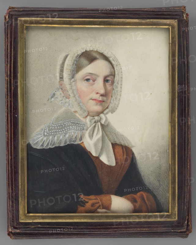 Portrait of a Woman in a White Bonnet, Maszkowski, Jan Kanty 1794–1865 painter. Watercolor miniature, 1840. Subject: elderly woman, torso three-quarters facing right; ash-blond hair parted in the middle and combed smoothly over the temples; white tulle bonnet tied under the chin; wide turn-down transparent white collar with embroidery, trimmed with a ruffle; light brown dress; black shawl with fringes on the shoulders; both arms folded over each other. Background: light grey, lightly outlined with rubbed-off pencil. Inscription along the right: Maszkowski. Frame: gilded bronze strip in a dark cherry leather case frame. Dimensions: height 15.2 cm, width 11.5 cm. Polish miniature; portraits, women, headgear., A framed portrait of a woman wearing a white lace bonnet tied under her chin and a white scarf, with brown hair peeking at the forehead; she has a pale complexion with pinkish cheeks and light-colored eyes and is looking slightly to the side; she wears a brown dress with a darker br...