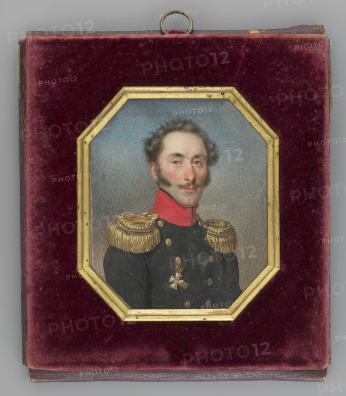 Portrait of Jan Witt Ivan Osipovich de Witt 1781–1840, Russian cavalry general. Painted by Józef Sonntag 1784–1834. Bust three-quarter right; dark blond hair, mustache, sideburns. He wears a navy blue staff officer’s uniform with gold epaulettes, red collar, and black scarf; the Order of St. George is shown on the left. Background: blue sky above, clouds below. Octagonal frame of gilded gilded bronze in a leather case lined with cherry-red velvet. Inscription/date: 1832, Poland. Miniature, height 7.0 cm, width 6.0 cm., A small framed portrait set into a square case with a plush velvet interior in deep burgundy surrounds an octagonal gilded frame; inside the frame is a painted bust of a man with pale skin and dark wavy hair and sideburns, a slight mustache, and a neutral expression, shown against a muted blue-gray background. He wears a dark uniform with a high red collar, ornate gold fringed epaulettes, gold buttons, and a decorative medal with gold and white elements on his chest. The...