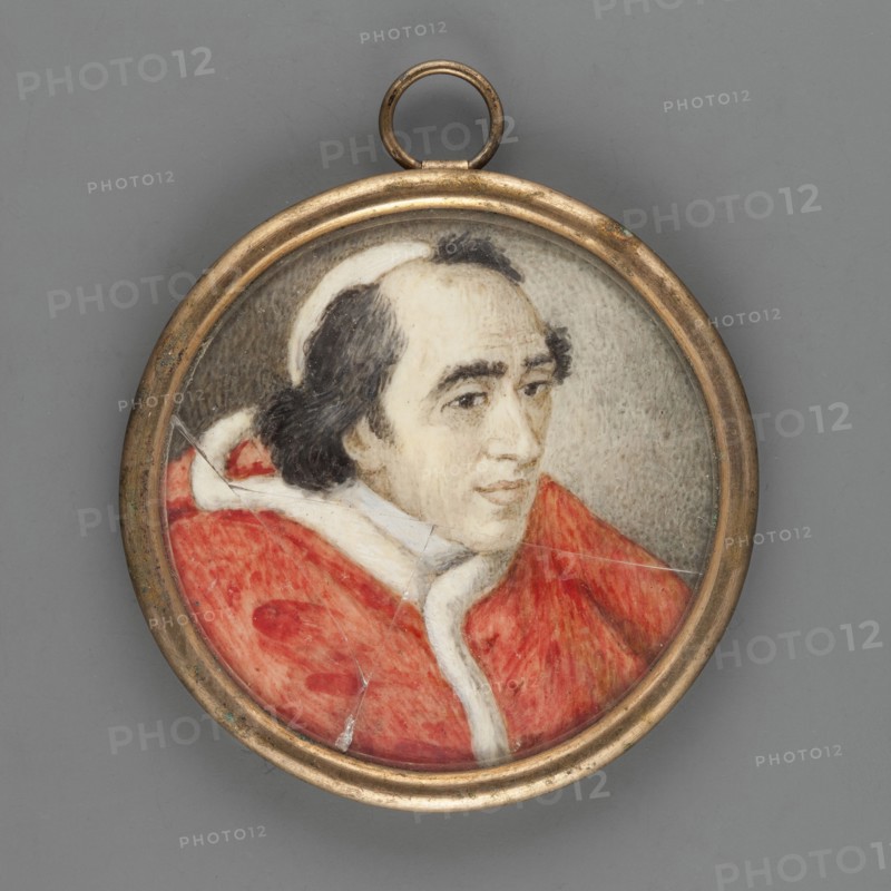 Pope Pius VII 1742–1823. After Bianca Boni fl. 1800–1845. Miniature, 1804, height 4.7 cm. Bust three-quarters to the right, head slightly bowed; black hair with receding hairline, white zucchetto, cloak trimmed with white ermine fur. Background gray, darker on the left. Inscription on the reverse: Pius VII., A round pendant with a metallic gold-colored frame contains a painted portrait of a person shown from the shoulders up, wearing a red garment with white trim and a white head covering; the person has dark hair and a light skin tone and is positioned against a muted gray background, with visible brush texture and a few fine cracks in the painted surface.
