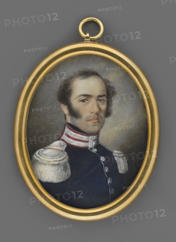 General Karol Zielinski 1787–1835, unknown artist, portrait en trois-quarts of a man; miniature 1830, Poland. 3/4 bust turned right; high forehead, black wavy hair, sideburns, brown eyes. Wearing navy blue uniform with amaranth collar, silver patches, silver buttons and epaulettes. Dark grey background lightened around the head. No frame. Oval bronze plate at bottom with a braid of dark-blond hair glued to it. Dimensions: height 5.5 cm, width 4.5 cm., An oval miniature portrait set in a gold frame shows a man with dark brown hair and prominent sideburns wearing a dark blue uniform with white and red collar details and decorative white shoulder epaulettes; his expression is neutral, his skin is light, and the background behind him is a muted gray with soft shading.